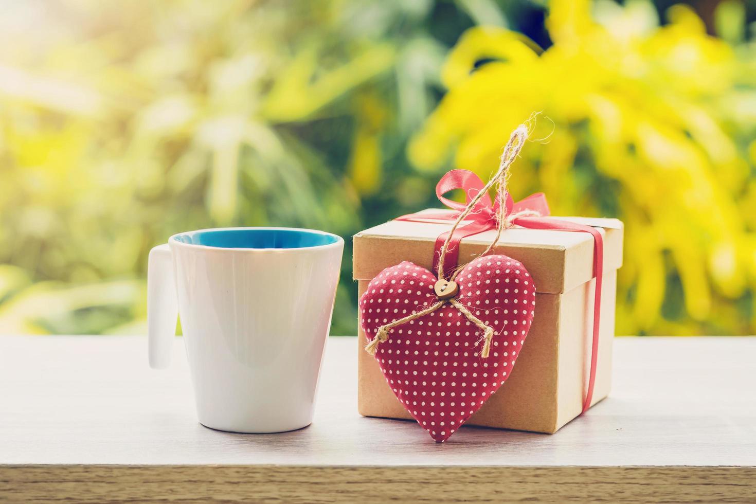 Happy father day concept coffee cup and gift box and heart on wood table with sunlight. photo