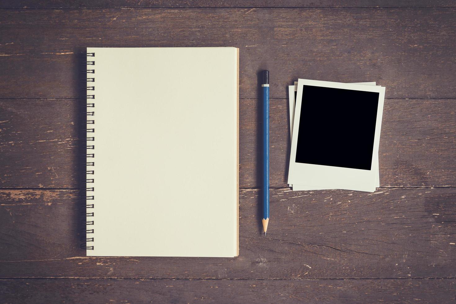 Blank Book open and photo frame on wood table with space.