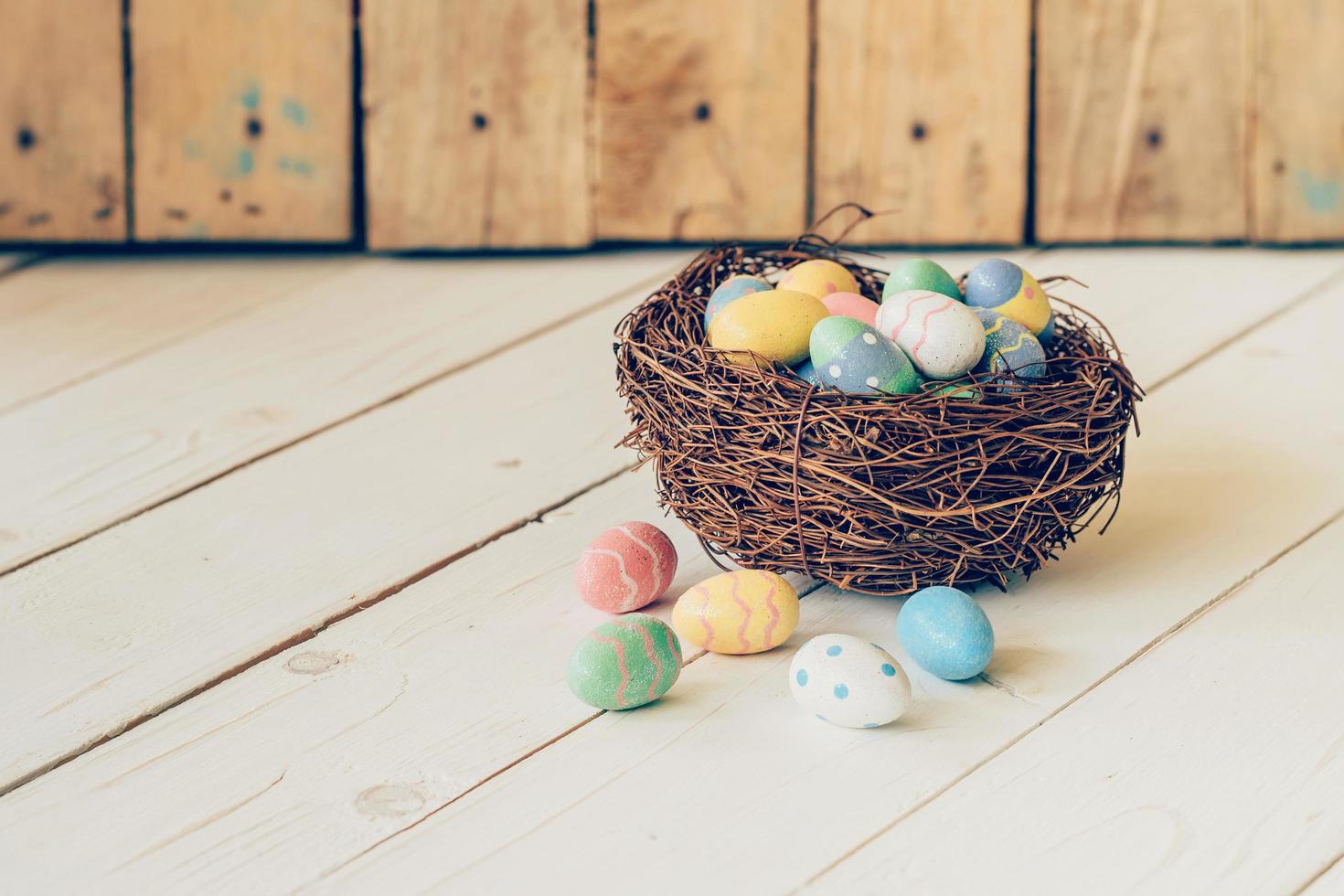 Colorful easter eggs in the nest on wood table background. photo