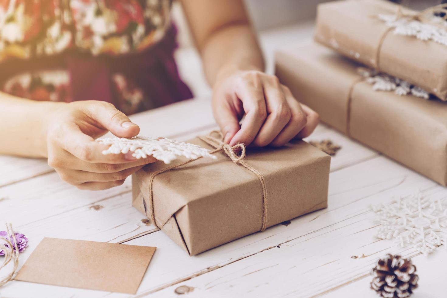 Woman hand making beautiful Christmas gift box at table photo