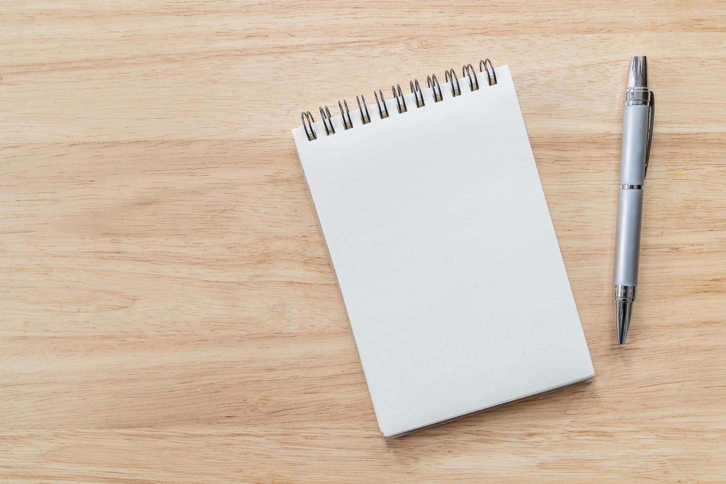 Top view of blank notebook with pen and natural light on wooden table. photo