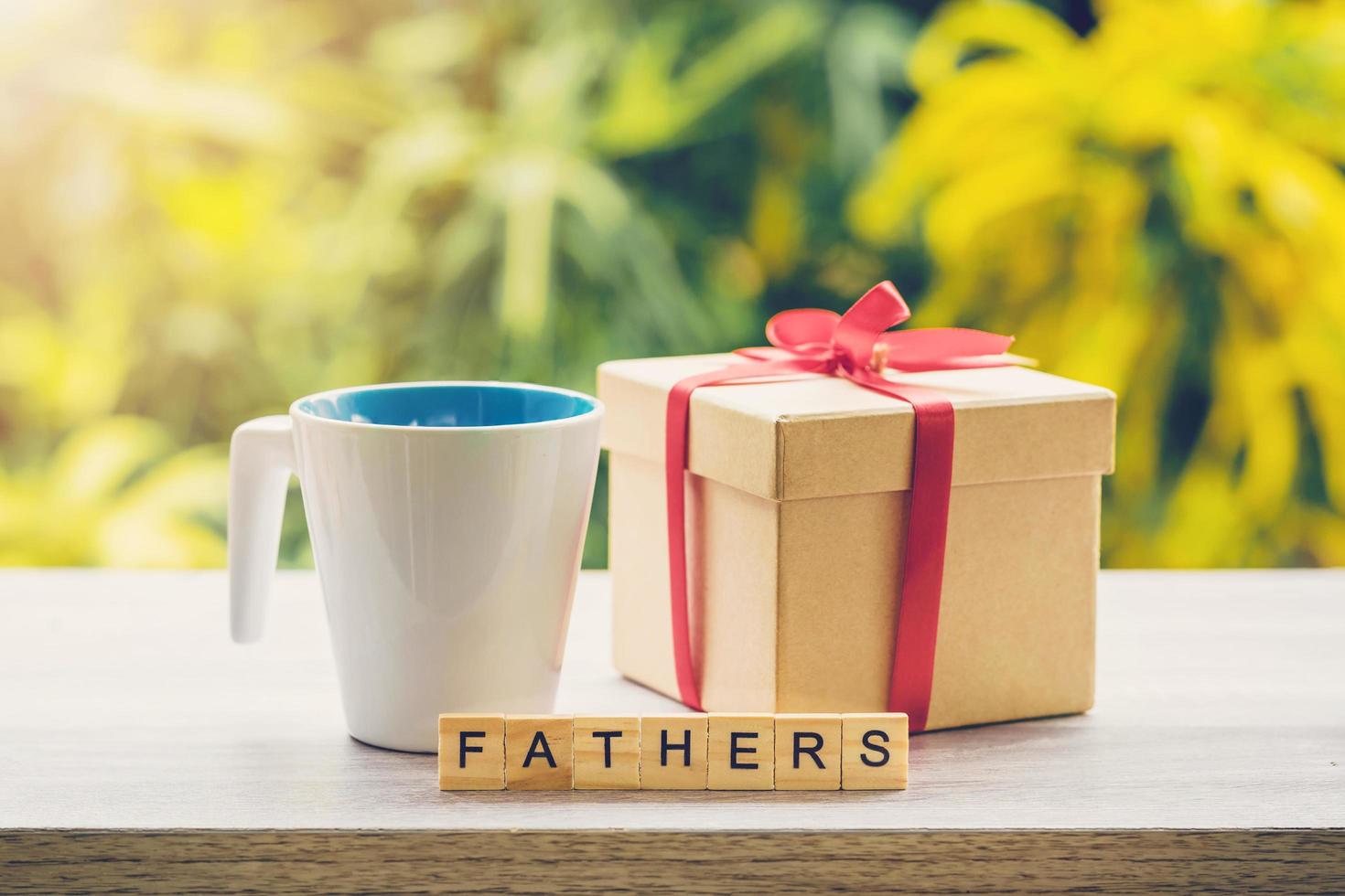 Happy father day concept coffee cup and gift box on wood table with sunlight. photo