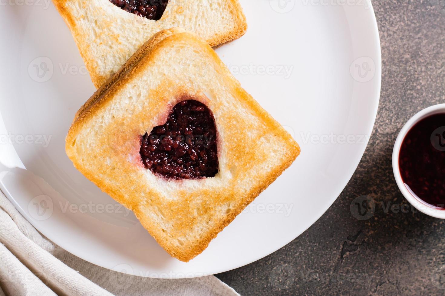 corazón conformado brindis con frambuesa mermelada en un lámina. comida para amantes parte superior vista. de cerca foto