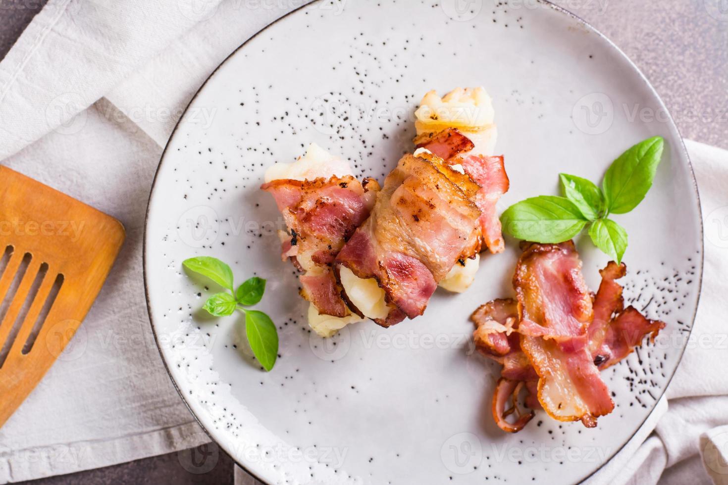 Mashed potatoes wrapped in fried bacon on a plate on the table. Top view. Closeup photo