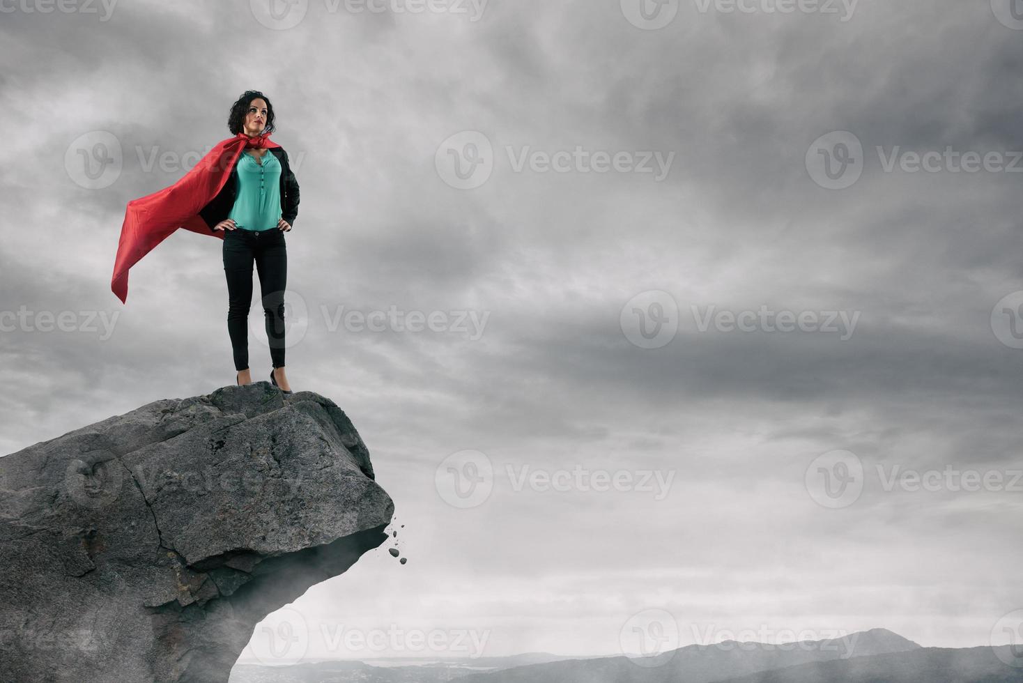 Business woman as a super hero on the peak of a mountain photo