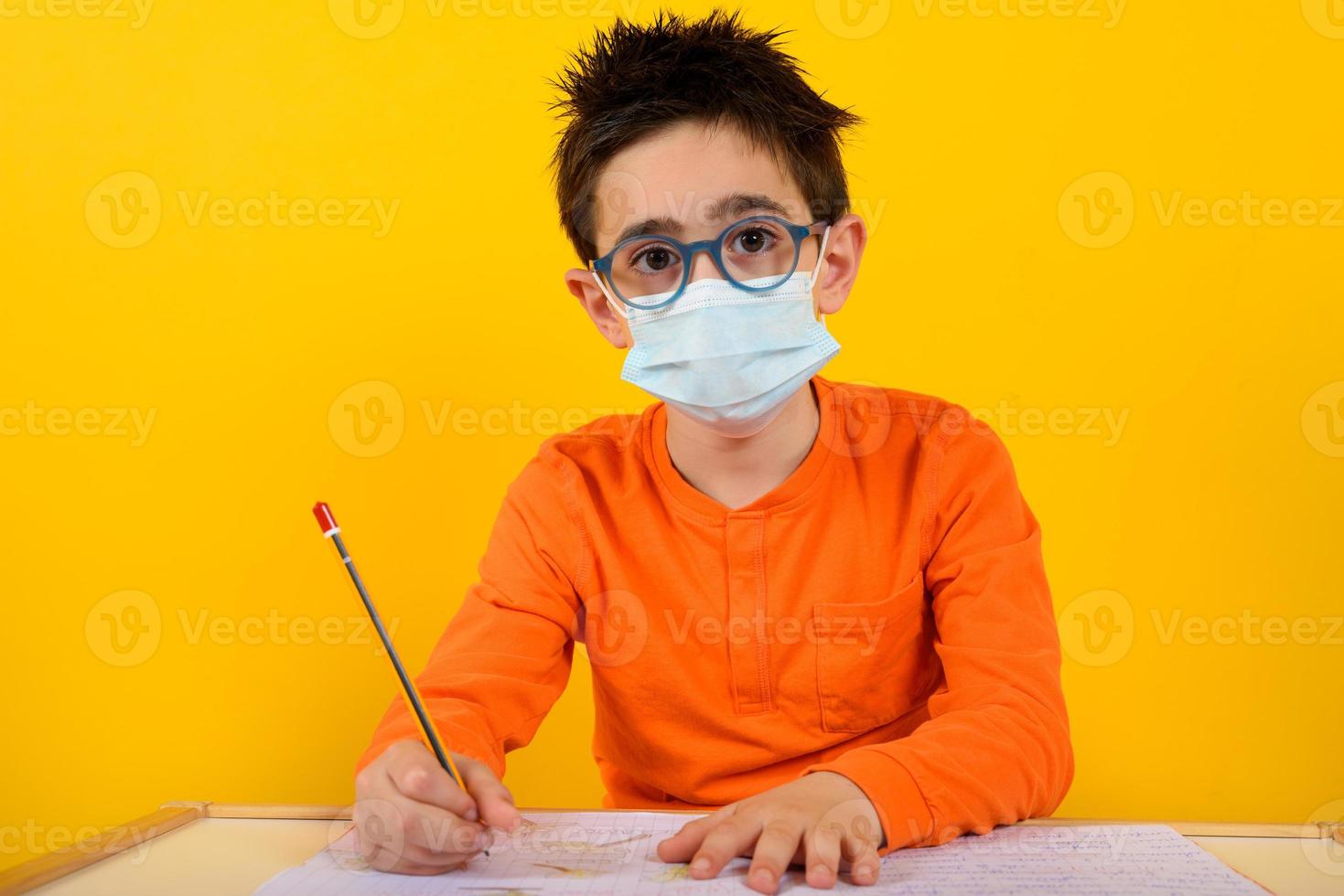 Child at school with face mask for covid-19 coronavirus. yellow background photo
