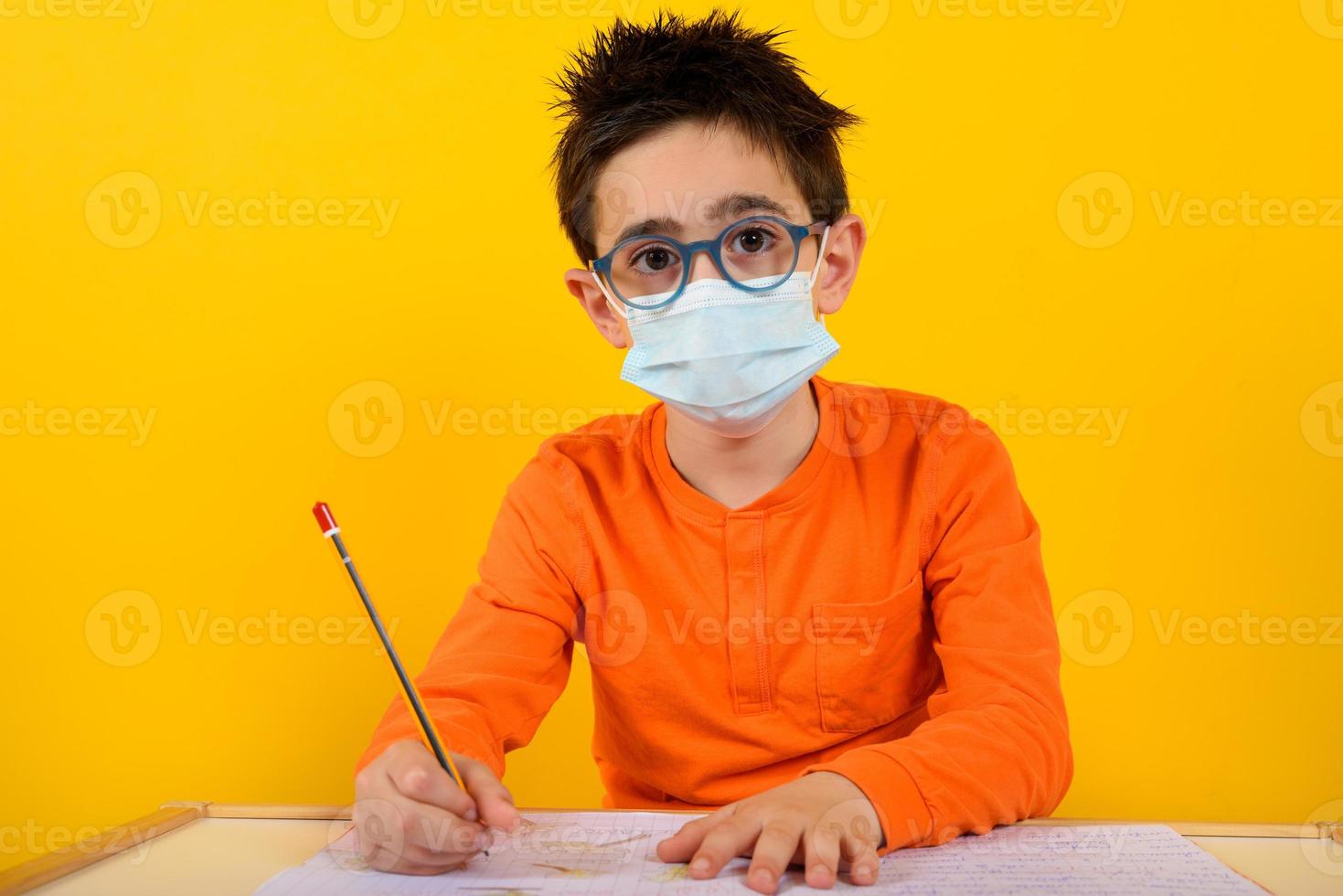 Child at school with face mask for covid-19 coronavirus. yellow background photo