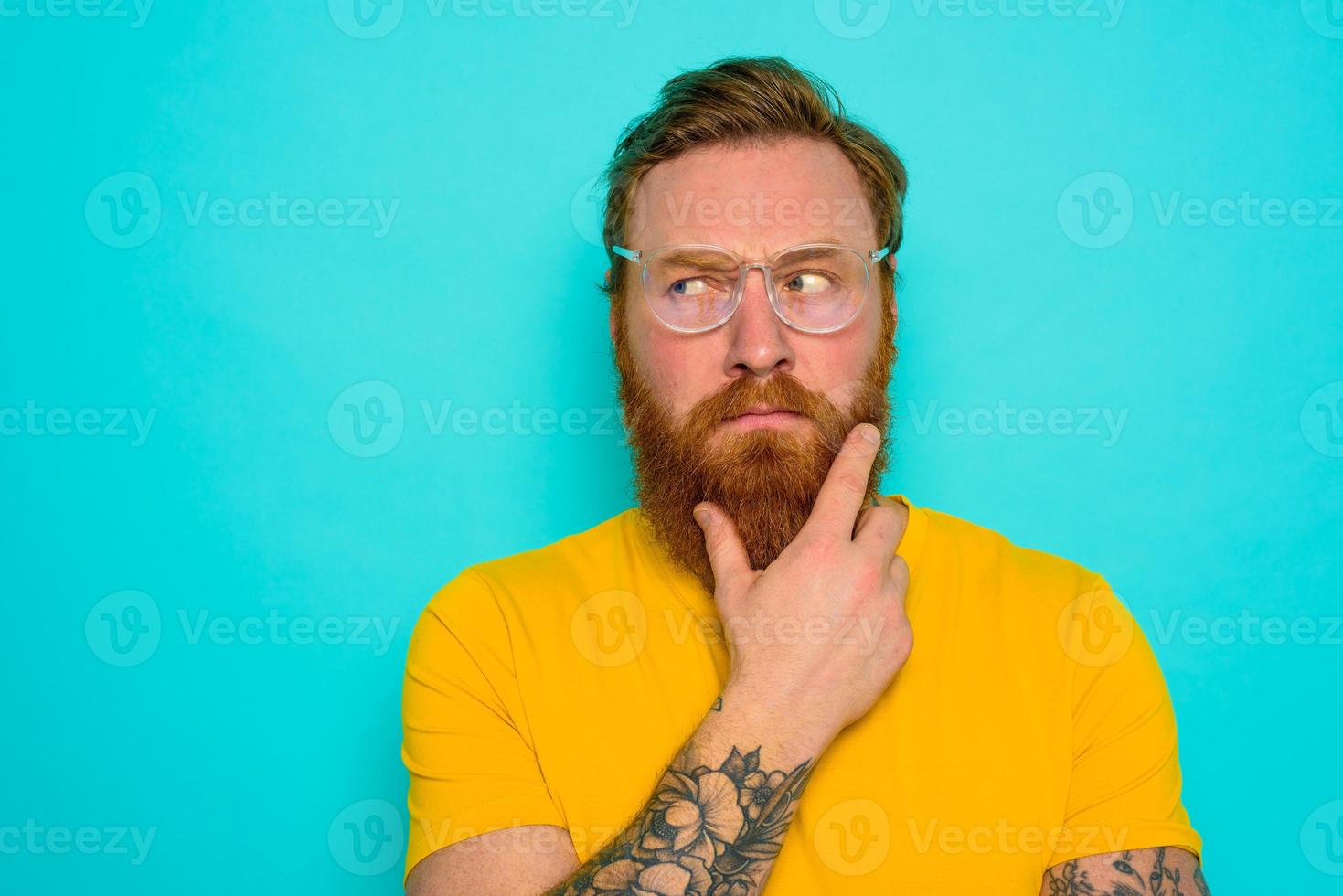 hombre con amarillo camiseta y barba es muy indeciso foto