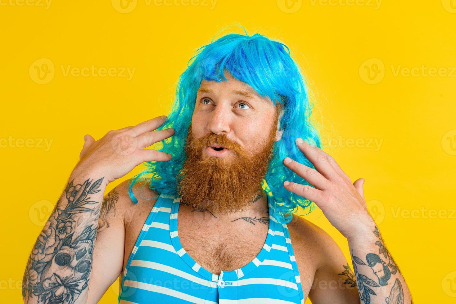 Happy man with life buoy, swimsuit and blue wig acts like a happy woman photo