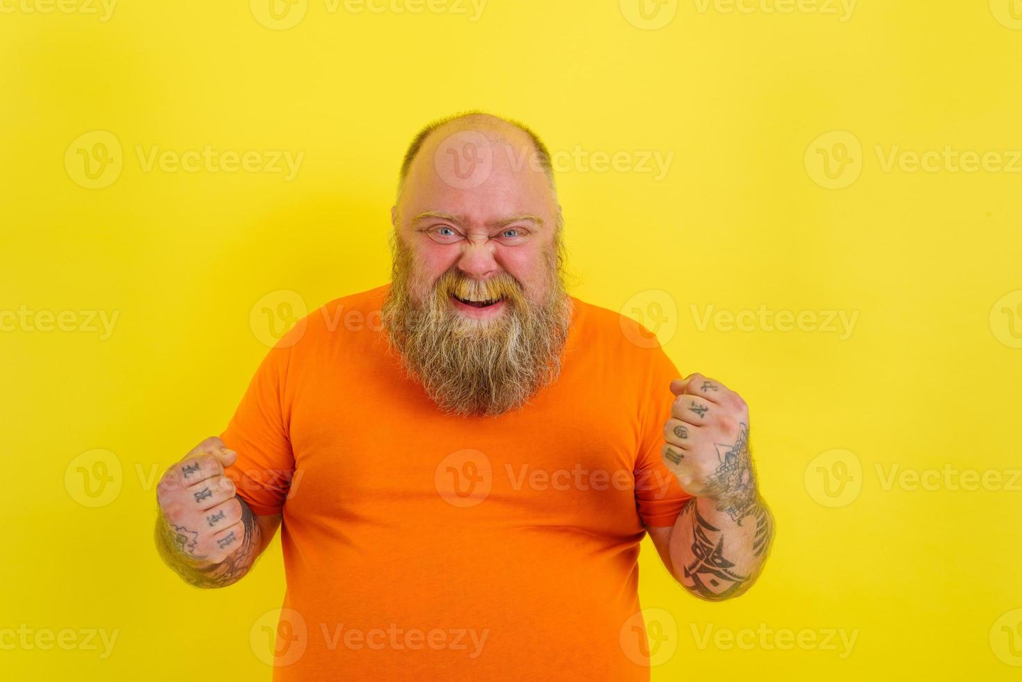 Happy man with beard and tattoos does a winning gesture with hands photo