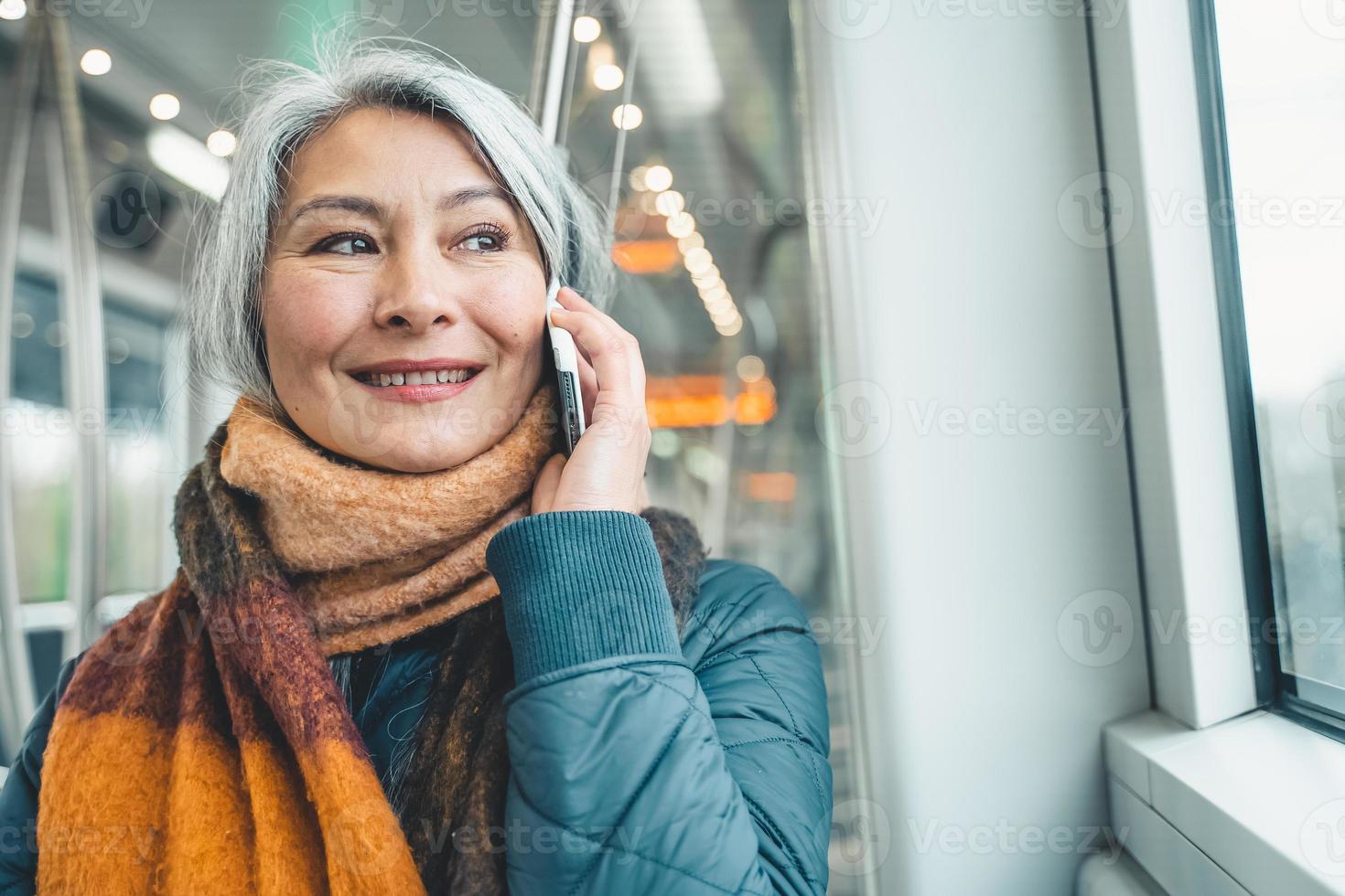 Senior woman send message with a mobile phone in a train photo