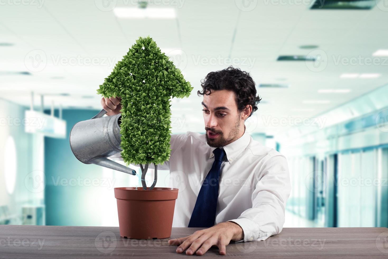 Businessman that watering a plant with a shape of arrow. Concept of growing of company economy . photo