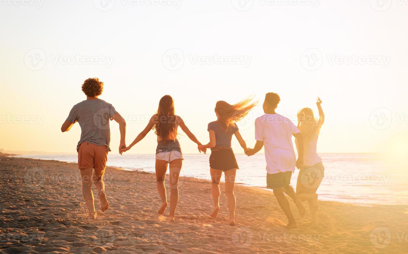 Group of friends run in the sea. Concept of summertime photo