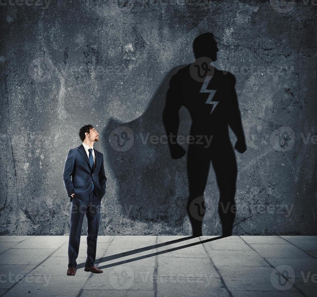 empresario con su sombra de súper héroe en el pared. concepto de poderoso hombre foto