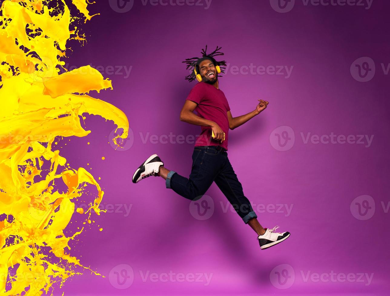 Boy with yellow headset listens to music and dances. emotional and energetic expression. Color spray effect photo