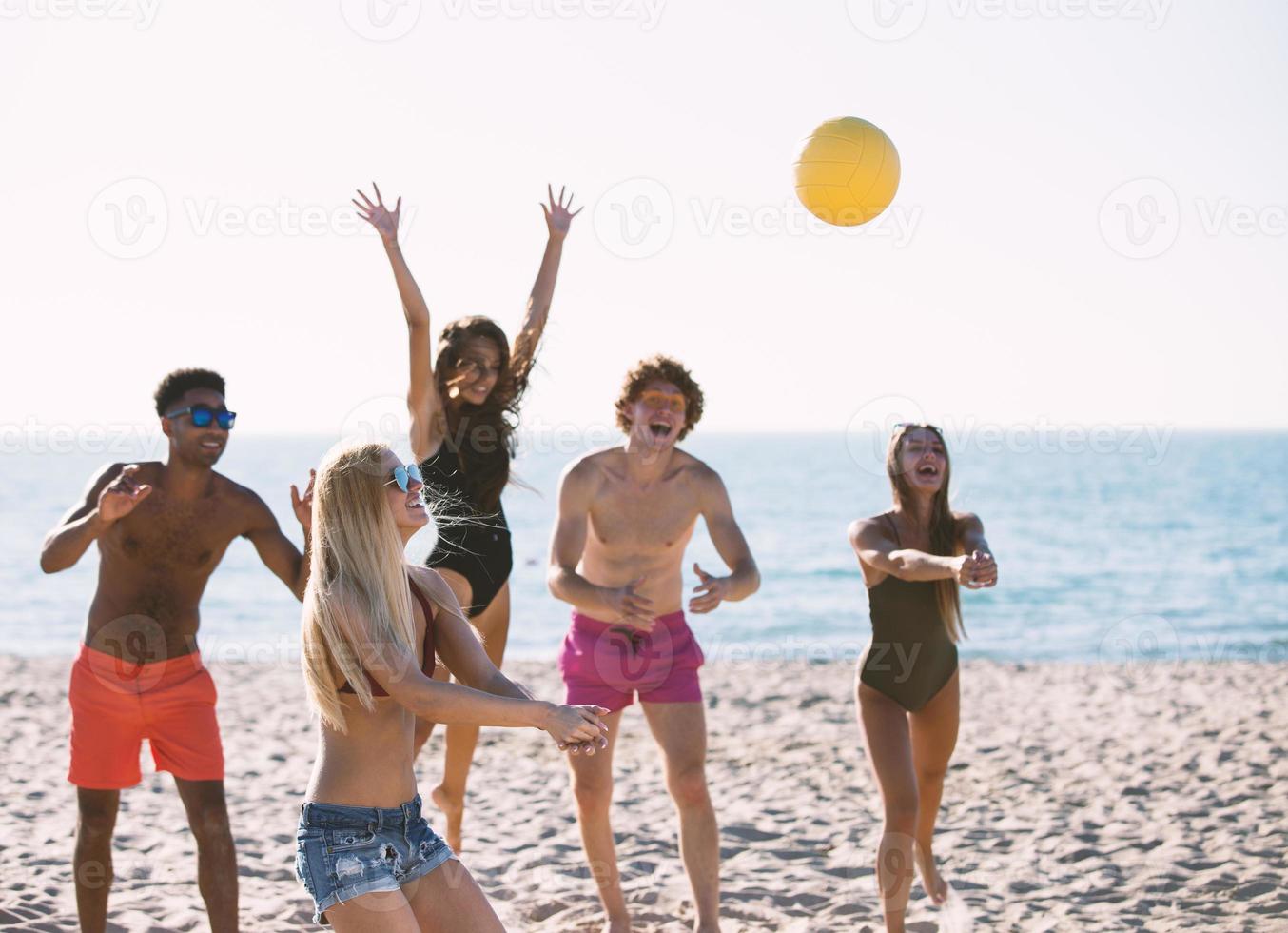 Group of friends playing at beach volley at the beach photo