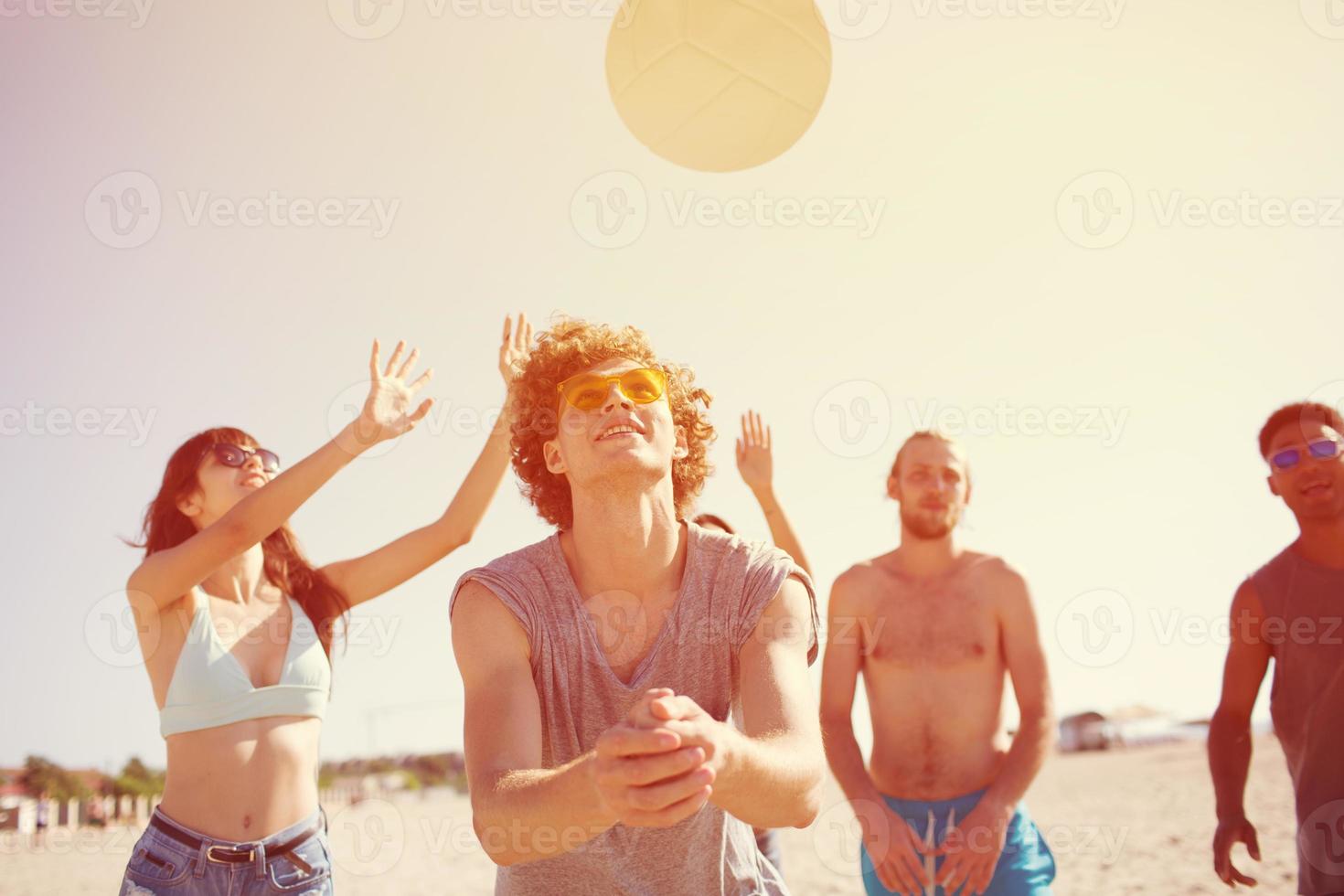 Group of friends playing at beach volley at the beach photo