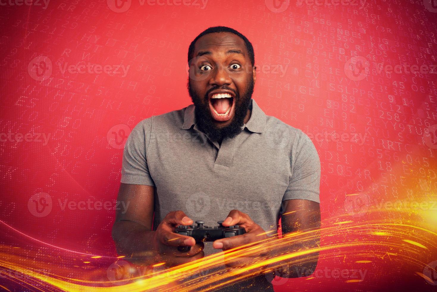 Happy man plays with a videogame on red background photo