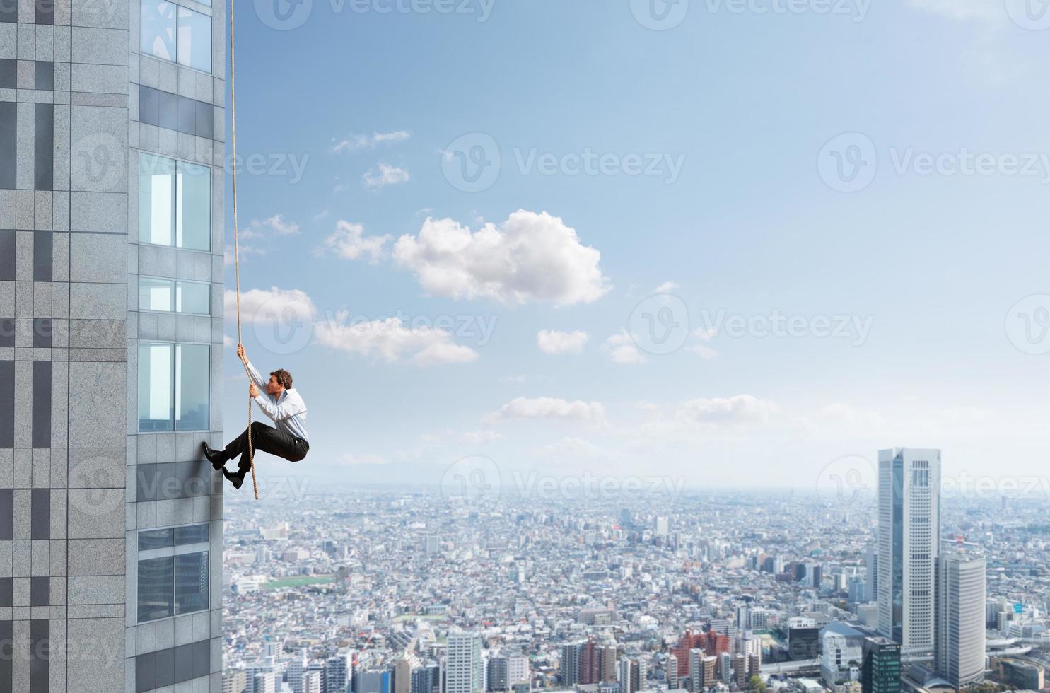Businessman climbs a building with a rope. Concept of determination. photo