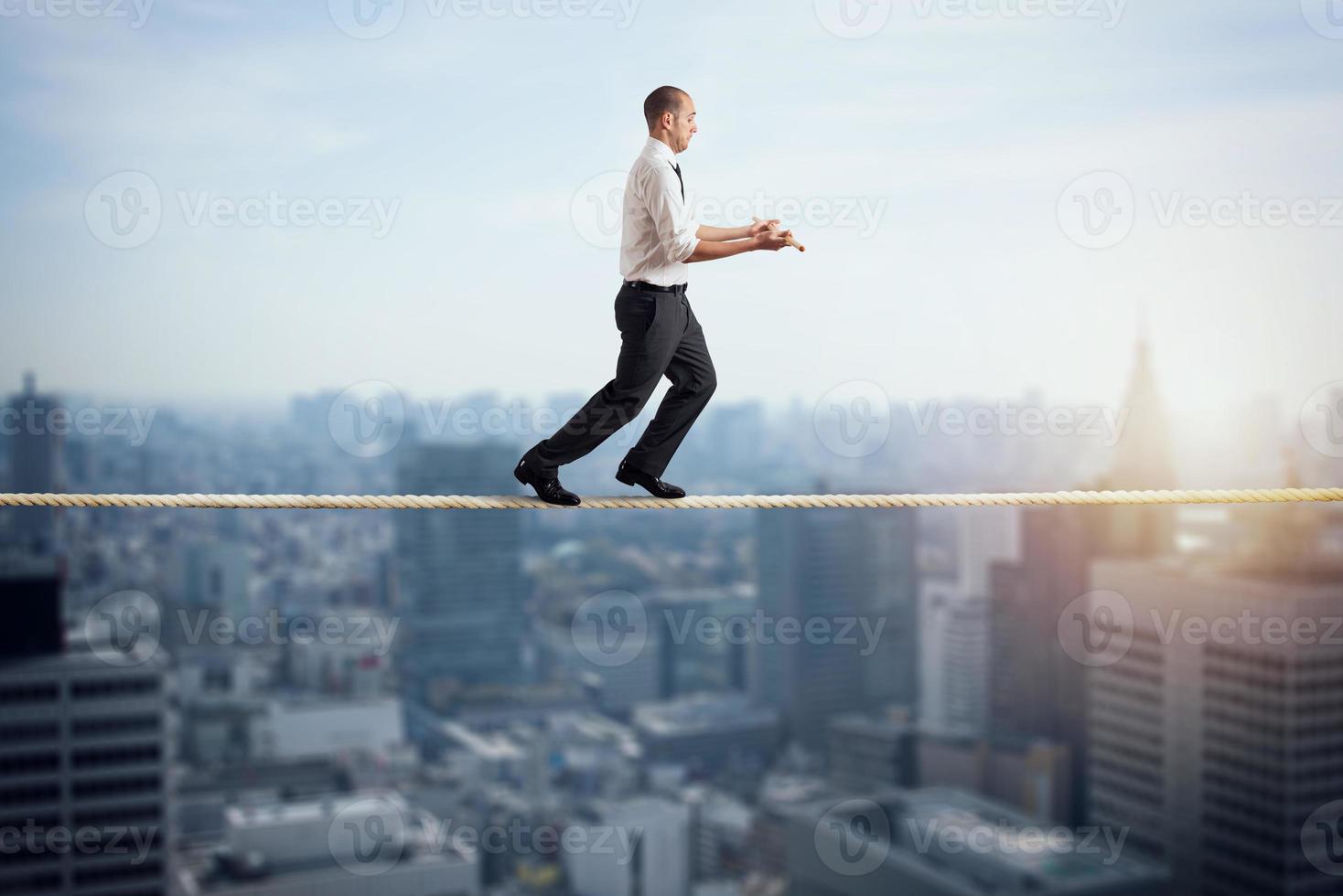 Worry man in balance walking on a rope over a city photo