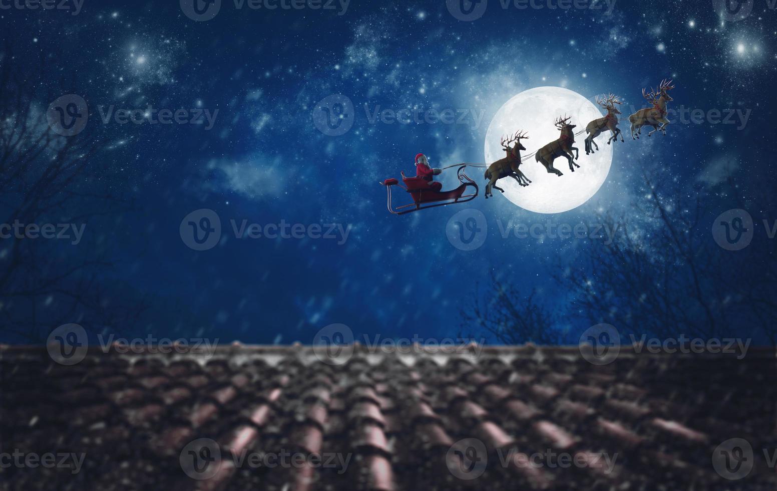 Santa Claus on his sleigh, pulled by reindeer, flying at night to deliver gifts photo