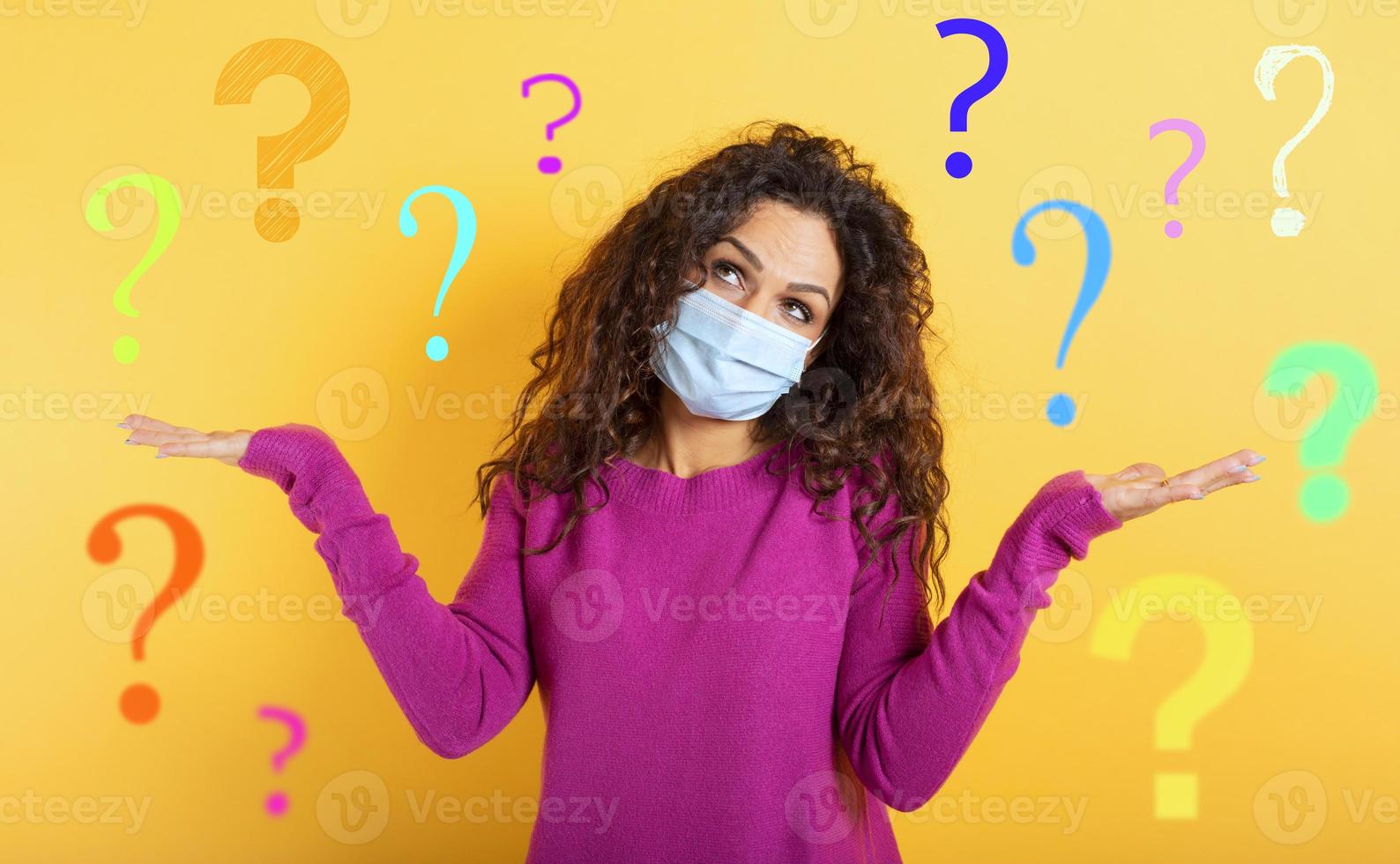 Girl with face mask has a lot of question about covid 19. Yellow background photo