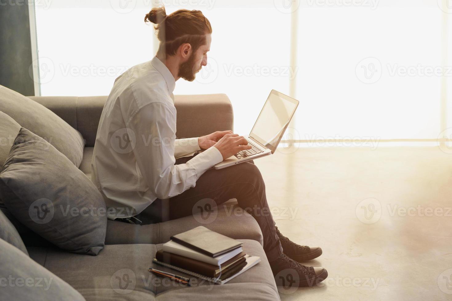 Businesman works on sofa with his laptop. he is in smart working photo