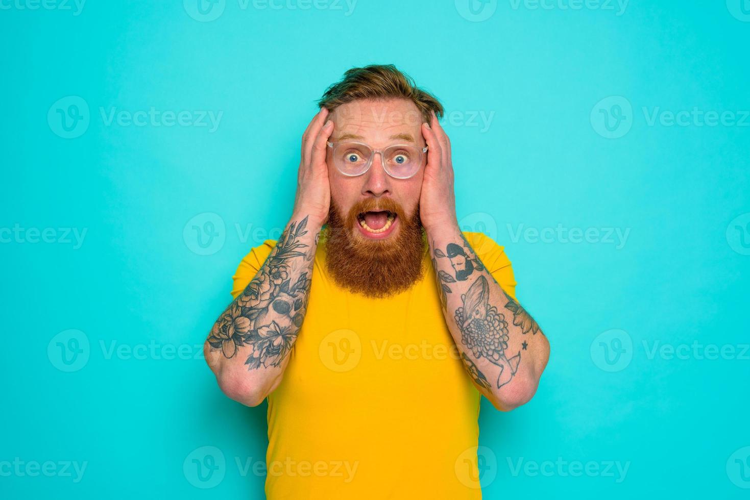 Man with yellow t-shirt and beard is shocked about something photo