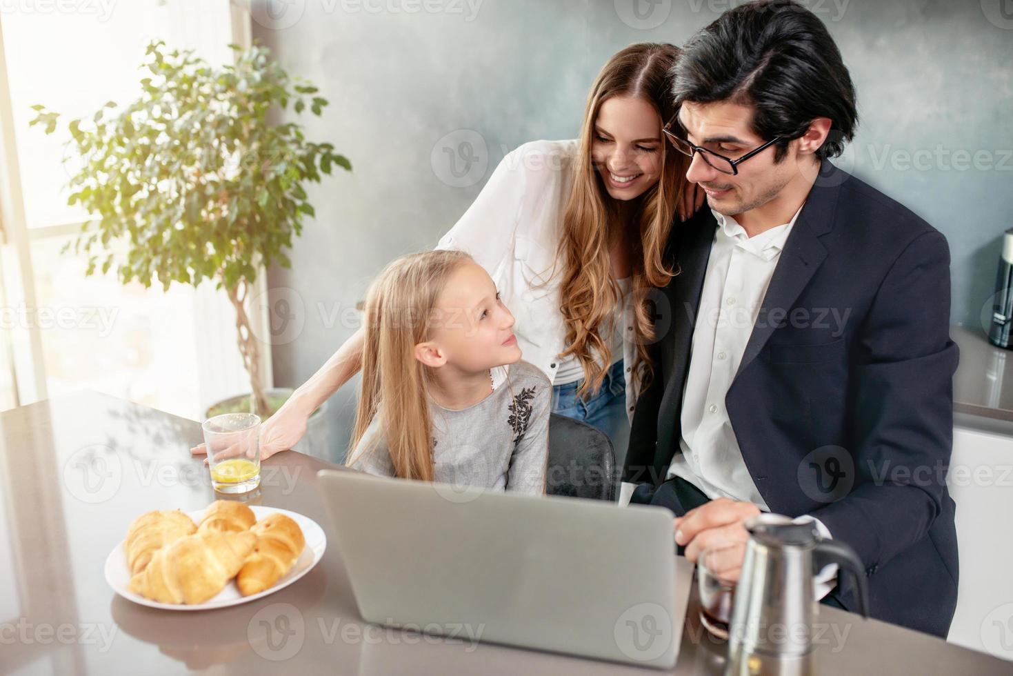 Happy little girl watching a movie on the computer with her father and mother photo