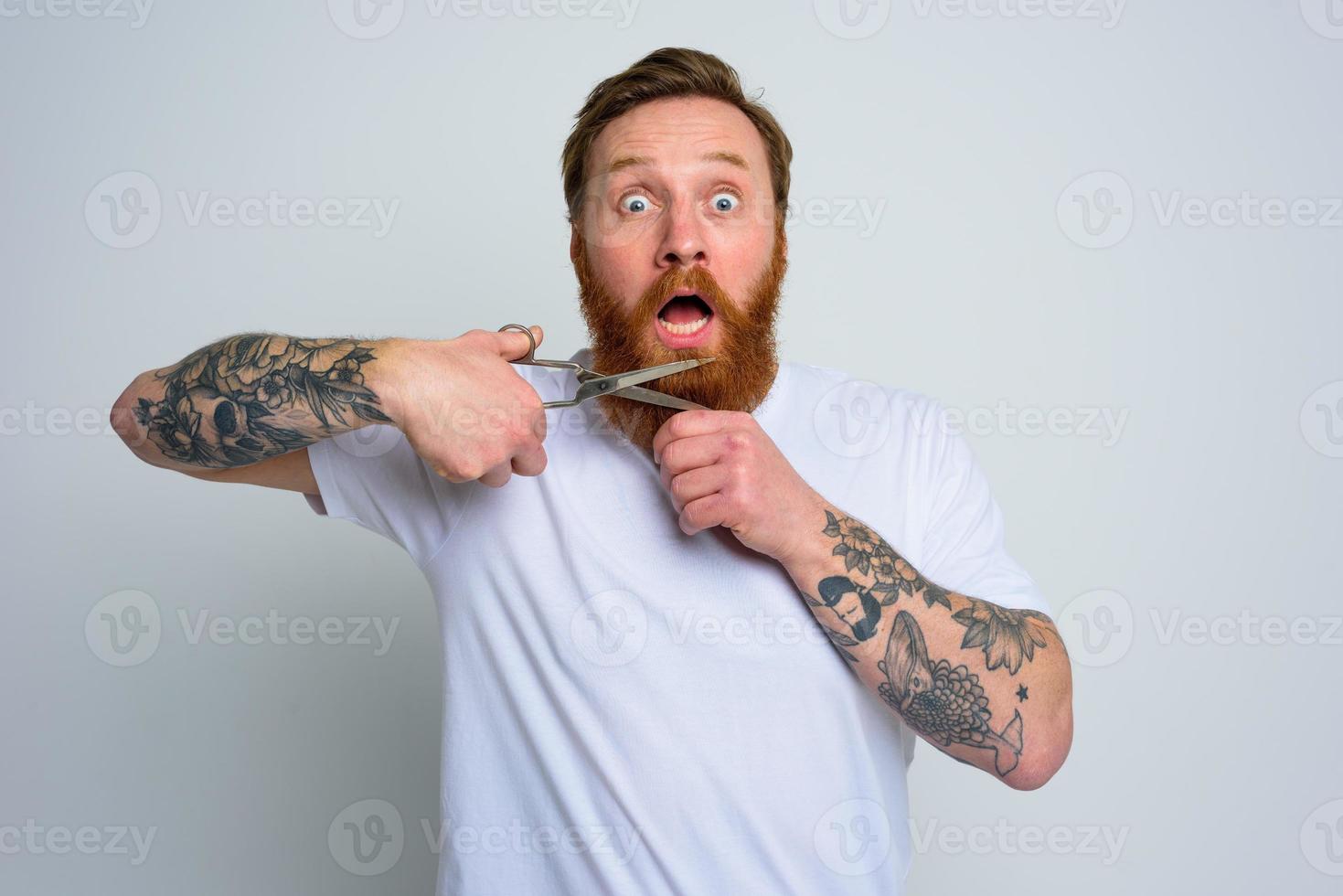 Amazed man with scissors doees not want to cut the beard photo