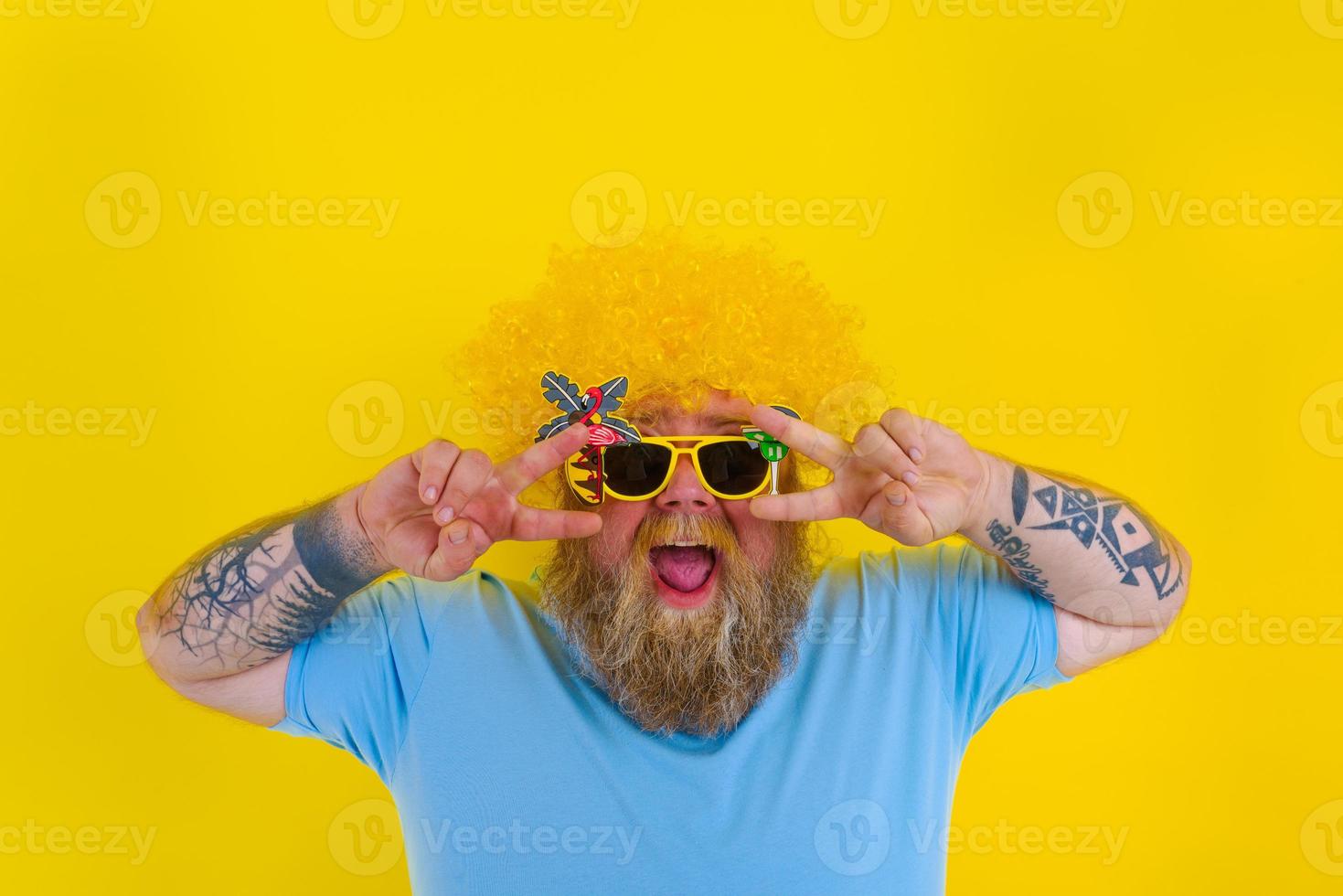 Fat man with wig in head and sunglasses dances photo