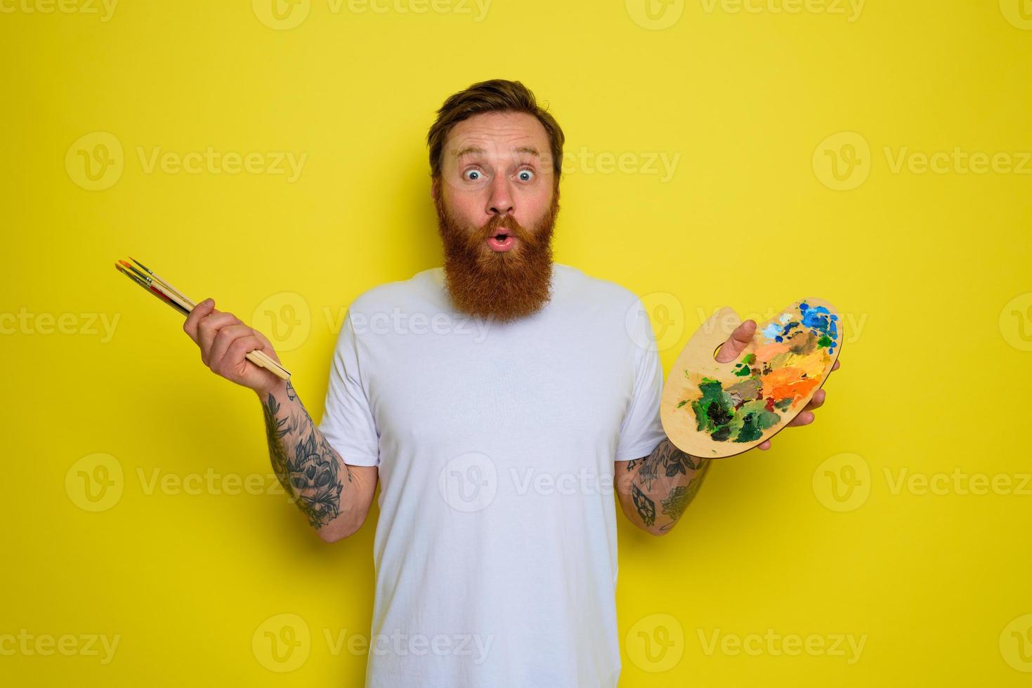 Wondered man with beard and tattoo is ready to draw with brushes photo