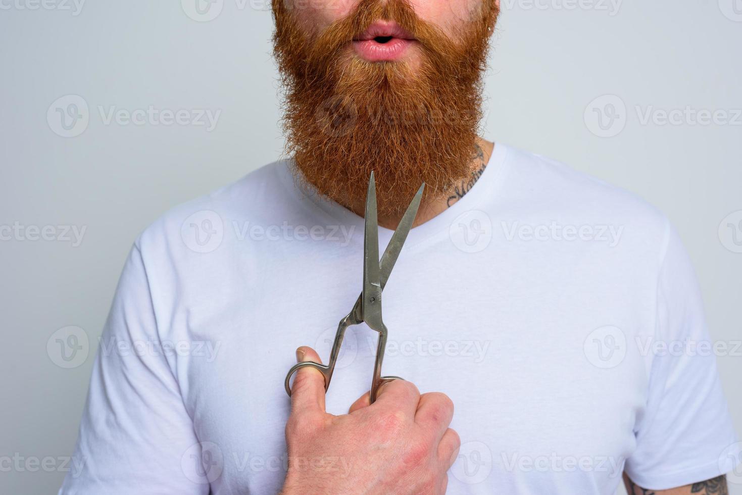 Wondered man with scissors is ready to cut the beard photo