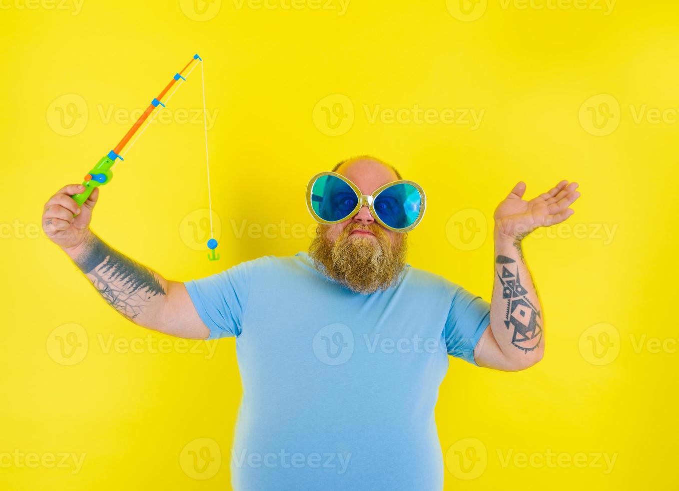 Fat man with beard and sunglasses is unhappy with the fishing rod photo