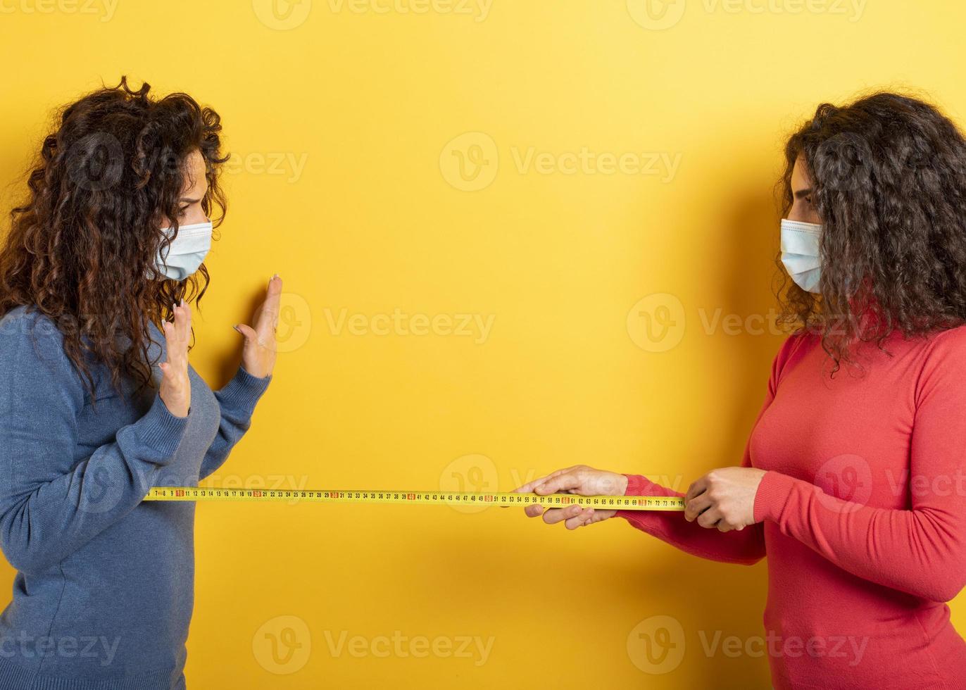 Friends keep distance between them of 1 meter. Concept of codiv-19 rules to avoid pandemic. yellow background photo