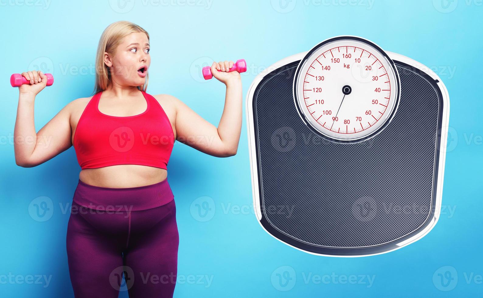 Fat girl does gym but is worried because she does not decrease her weight. cyan background photo