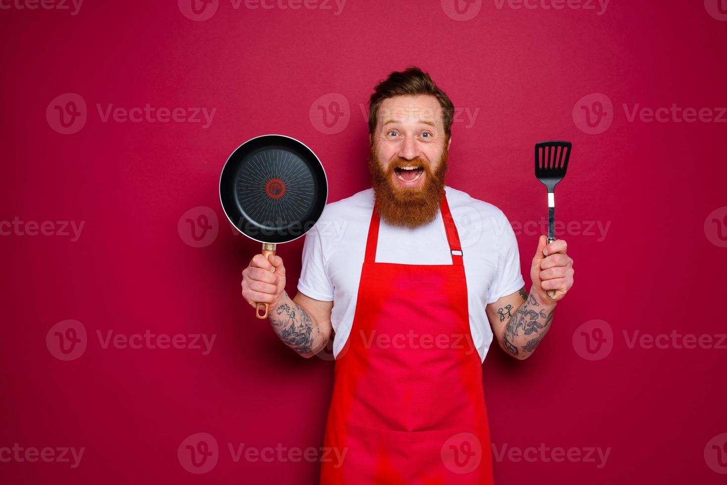 Happy chef with beard and red apron is ready to cook photo