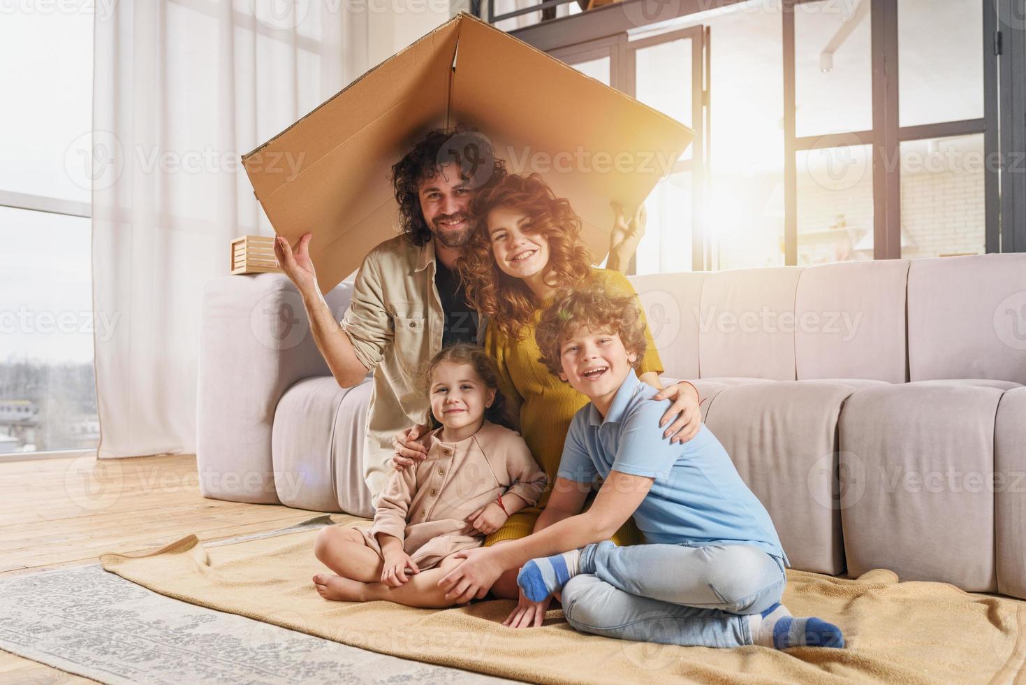 Happy family play together under a cardboard roof photo