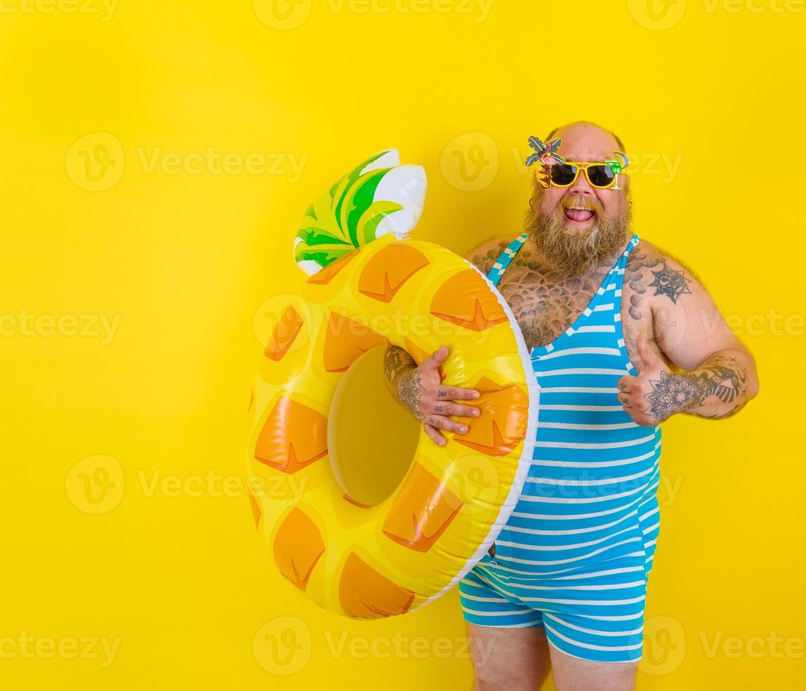 Fat happy man with wig in head is ready to swim with a donut lifesaver photo