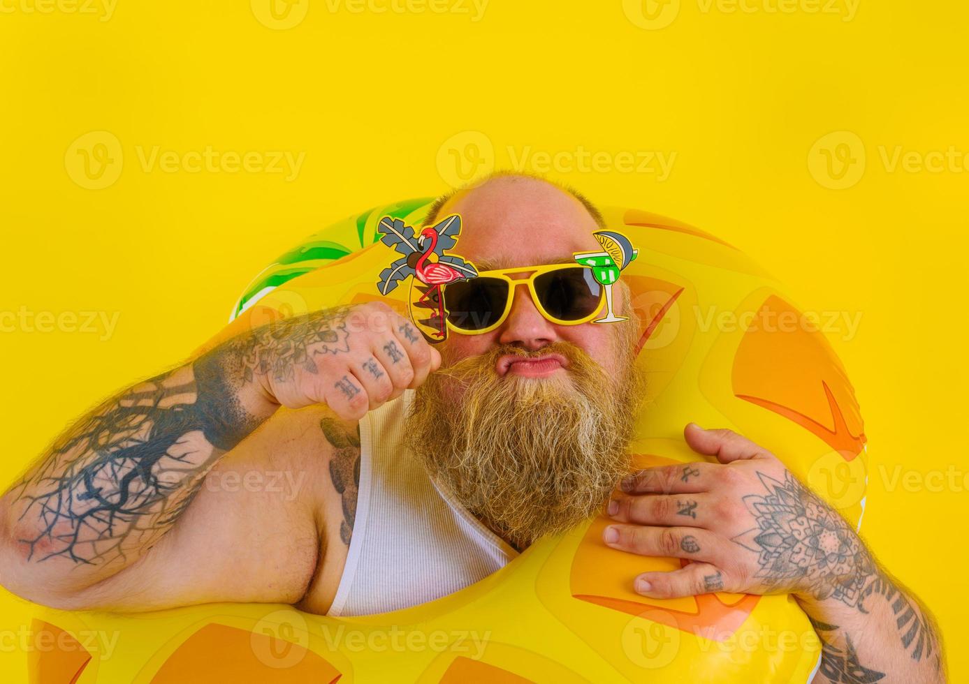 Fat thoughtful man with wig in head is ready to swim with a donut lifesaver photo