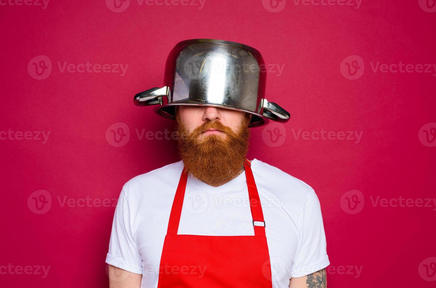 unhappy chef with beard and red apron plays with pot photo