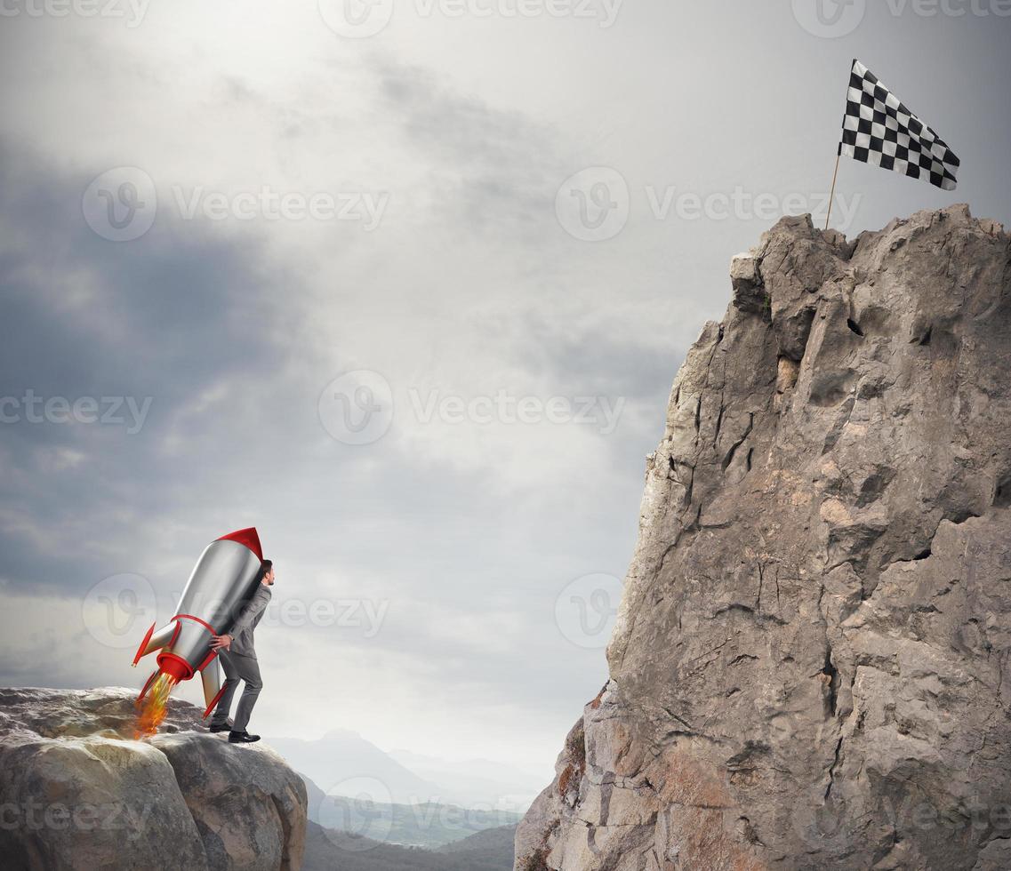 Determination and power businessman that holds a rocket to reach the flag photo