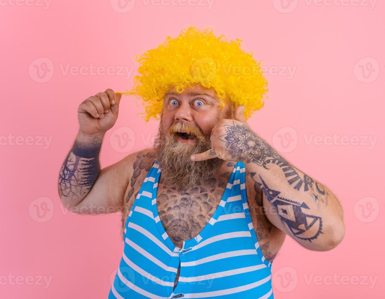 Amazed man with yellow wig and swimsuit is ready to the summer photo