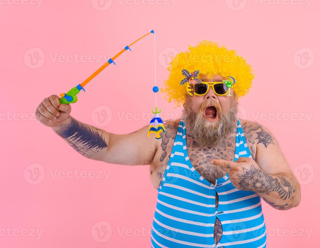 Fat amazed man with beard and sunglasses have fun with the fishing pole photo