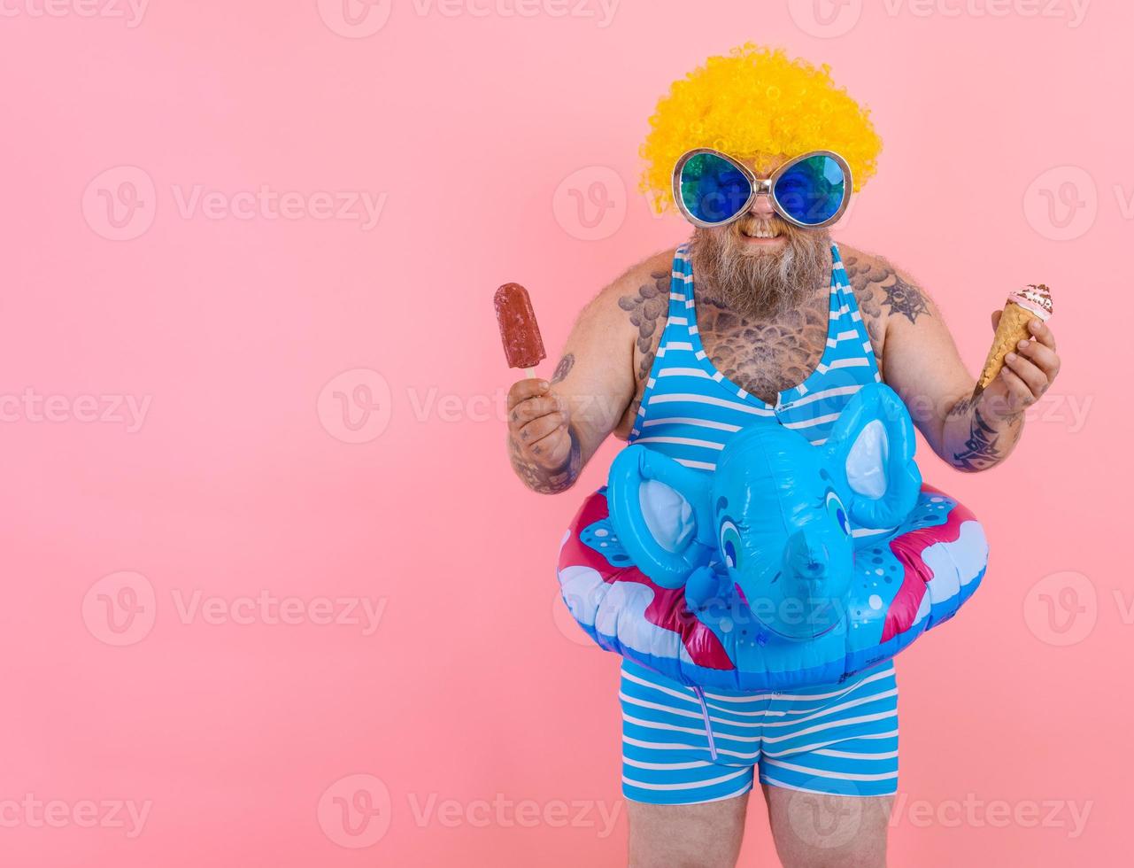 Fat man with beard and wig eats a popsicle and an icecream photo