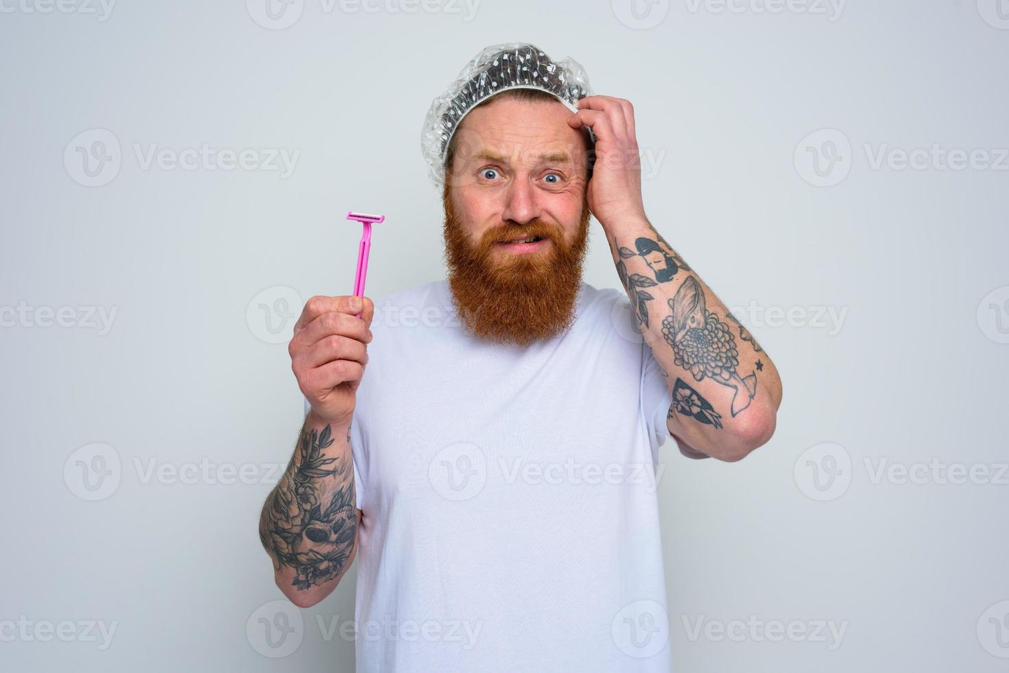 confused man wants to adjust the beard with a razor blade photo