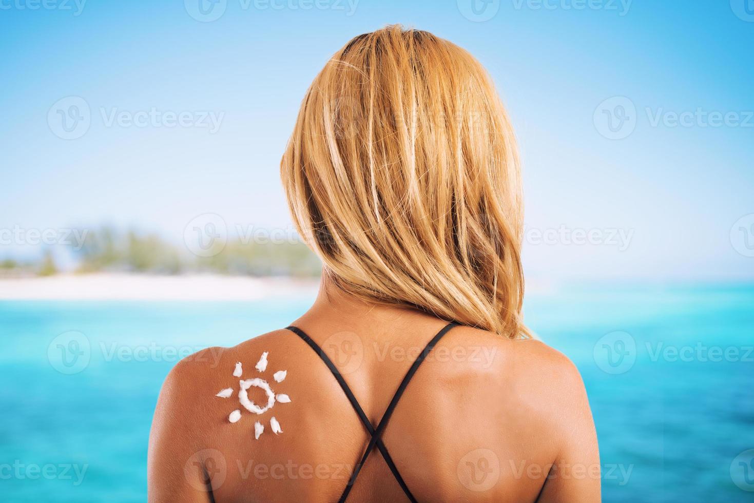 Girl in swimsuit with a sun made with sunscreen photo