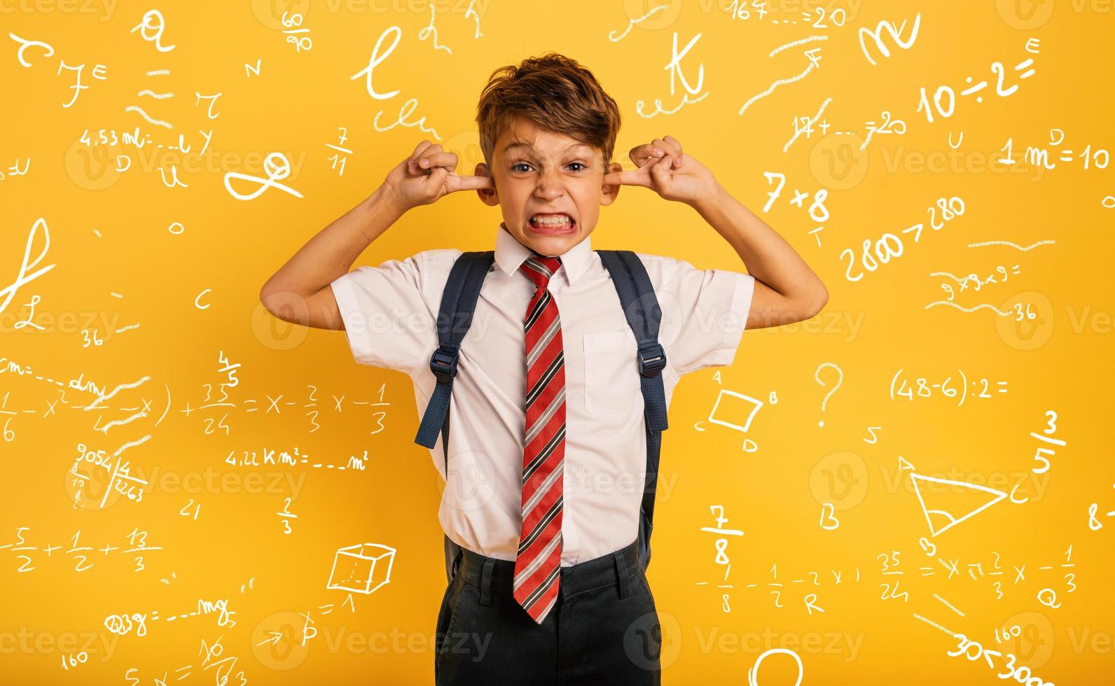 Student Child covers his ears because he does not want to hear noise. Yellow background photo