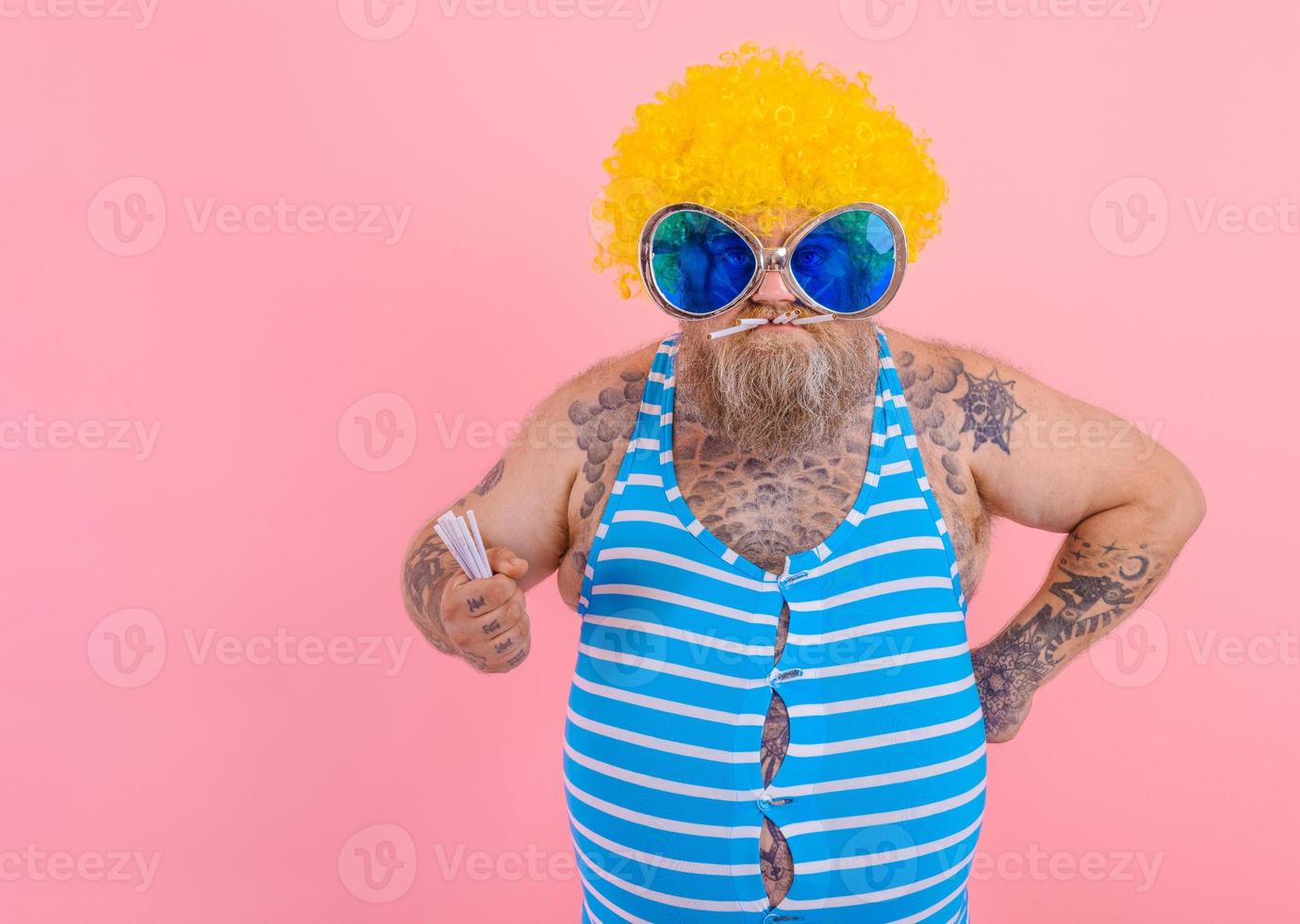 Fat angry man with beard and wig smokes cigarettes photo