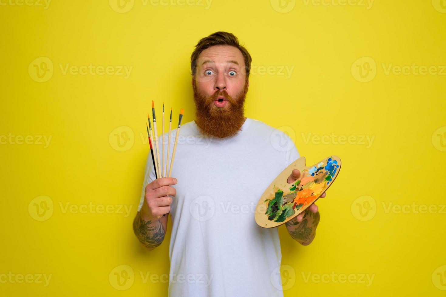 Wondered man with beard and tattoo is ready to draw with brushes photo